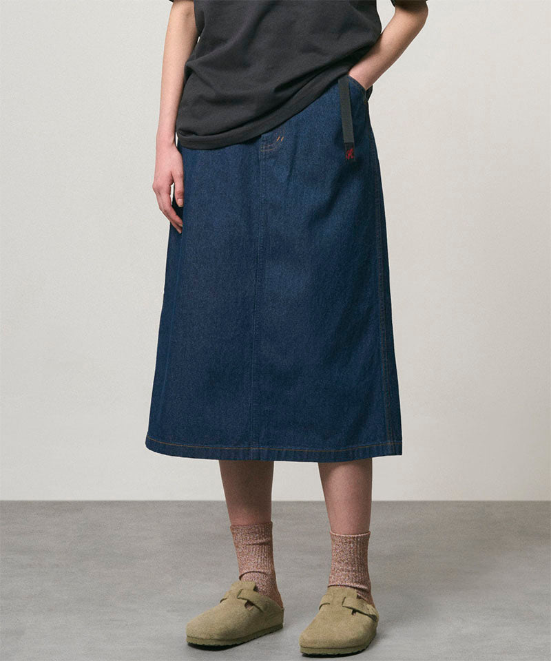Model wearing a rinsed indigo Gramicci Denim Carpenter Skirt and a black shirt on a light-tone background.