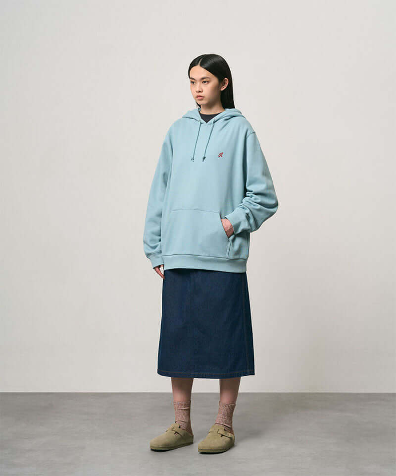 Model wearing a rinsed indego Gramicci Denim Carpenter Skirt and a light blue hoodie on a light-tone background.