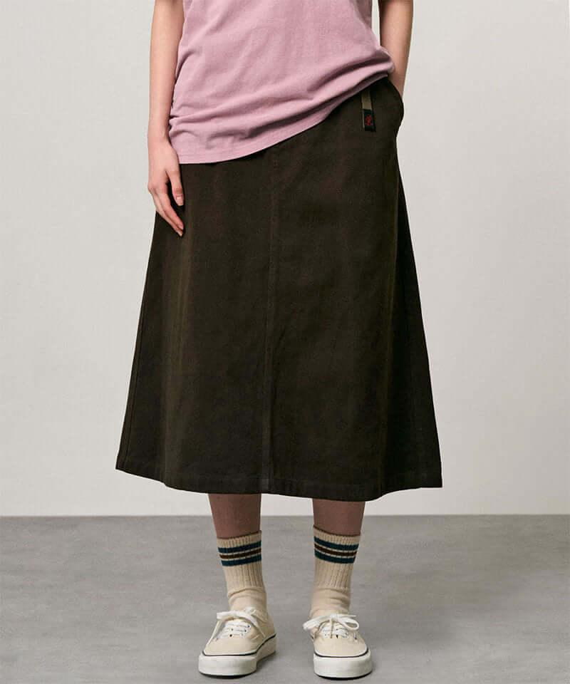 Model wearing a coffee colored Gramicci Venture Skirt and a pink shirt on a light-tone background.