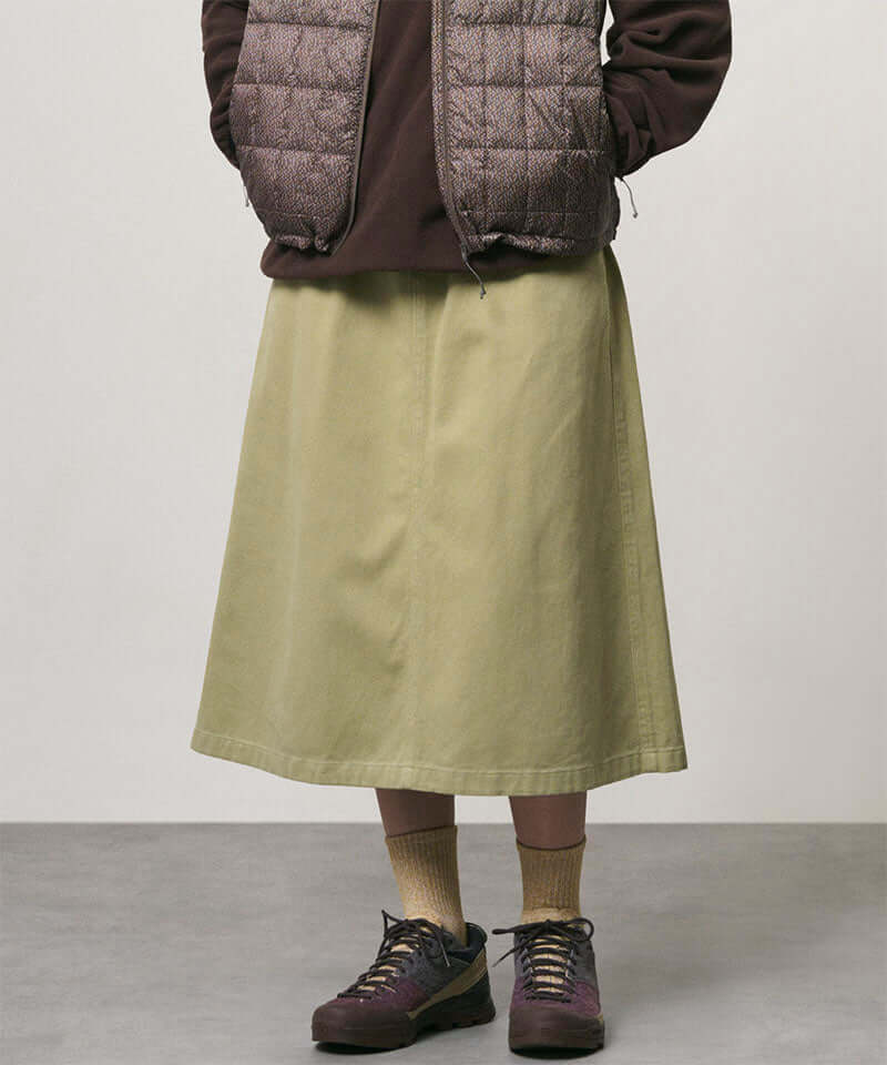 Model wearing a elm colored Gramicci Venture Skirt and a brown vest on a light-tone background.