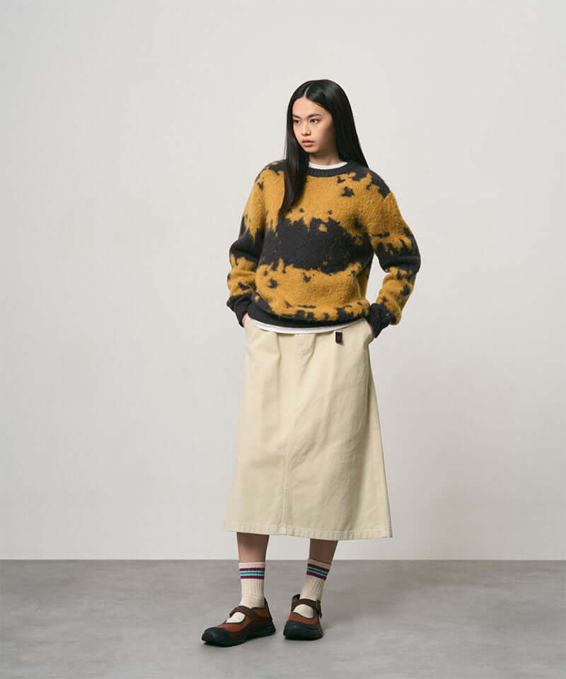 Model wearing a sand colored Gramicci Venture Skirt and a yellow and black tie-die sweater on a light-tone background.