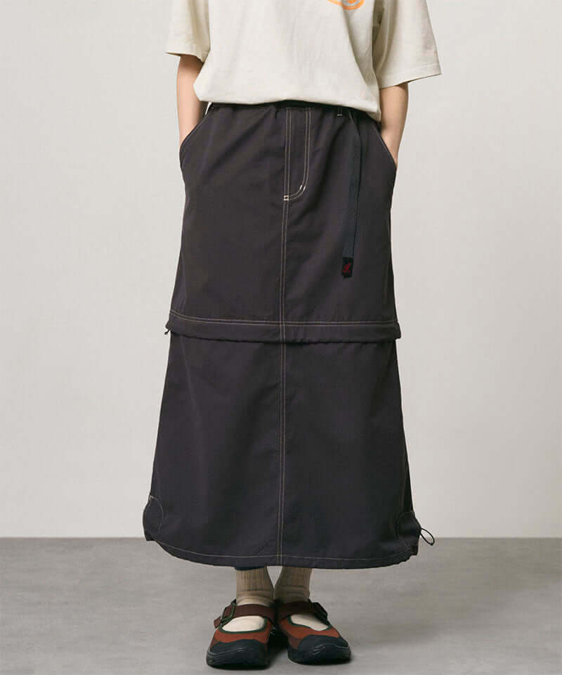 Model wearing a black women's Gramicci WR Convertible Skirt and a creme colored shirt on a light-tone background.