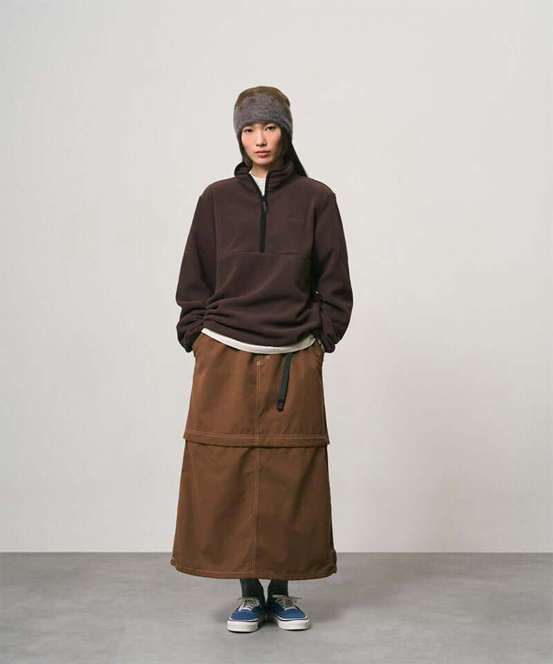 Model wearing a deep brown women's Gramicci WR Convertible Skirt and a dark brown shirt on a light-tone background.