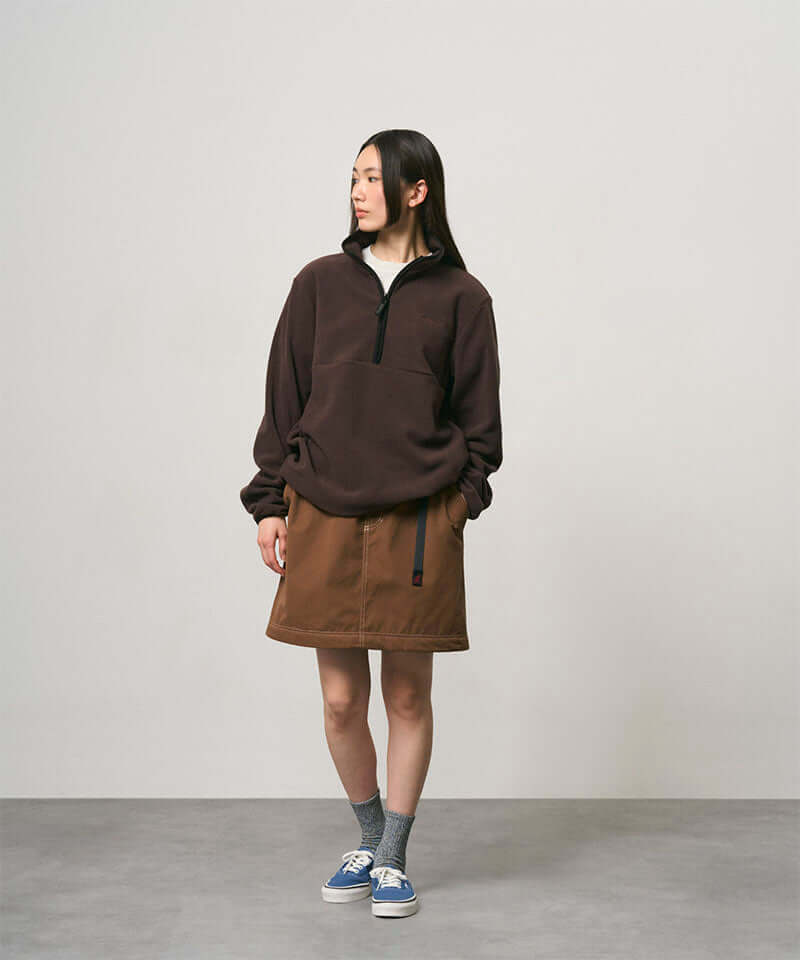 Model wearing a deep brown women's Gramicci WR Convertible Skirt and a dark brown jacket on a light-tone background.