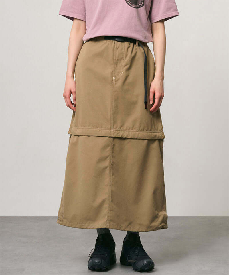 Model wearing a khaki colored women's Gramicci WR Convertible Skirt and a dusty pink shirt on a light-tone background.