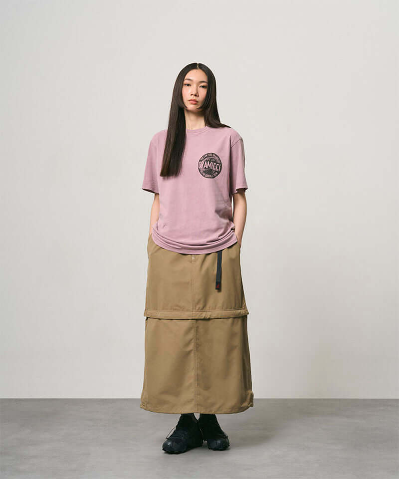 Model wearing a khaki colored women's Gramicci WR Convertible Skirt and a dusty pink shirt on a light-tone background.