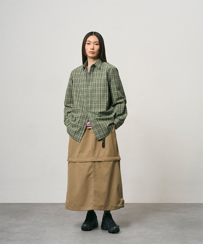 Model wearing a khaki colored women's Gramicci WR Convertible Skirt and a green plaid shirt on a light-tone background.