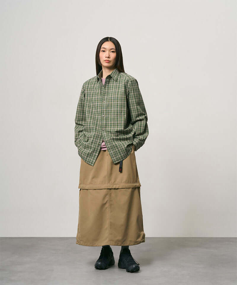 Model wearing a khaki colored women's Gramicci WR Convertible Skirt and a green plaid shirt on a light-tone background.