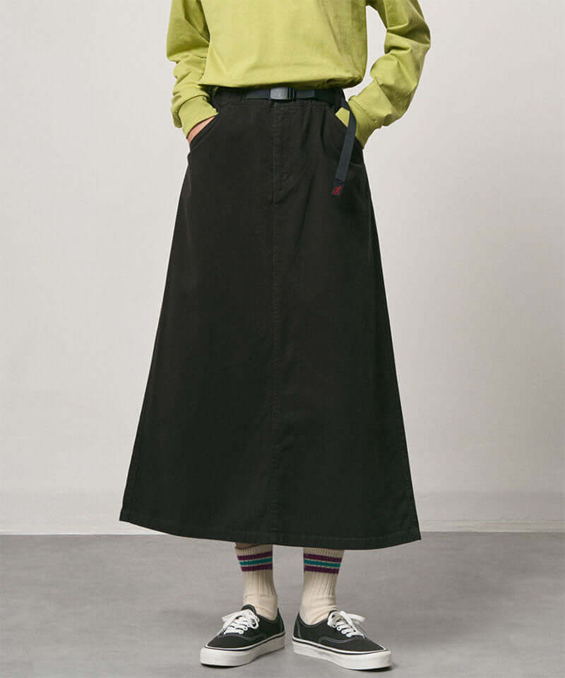 Model wearing a black Gramicci 5-Pocket Skirt and a brown vest on a light-tone background.