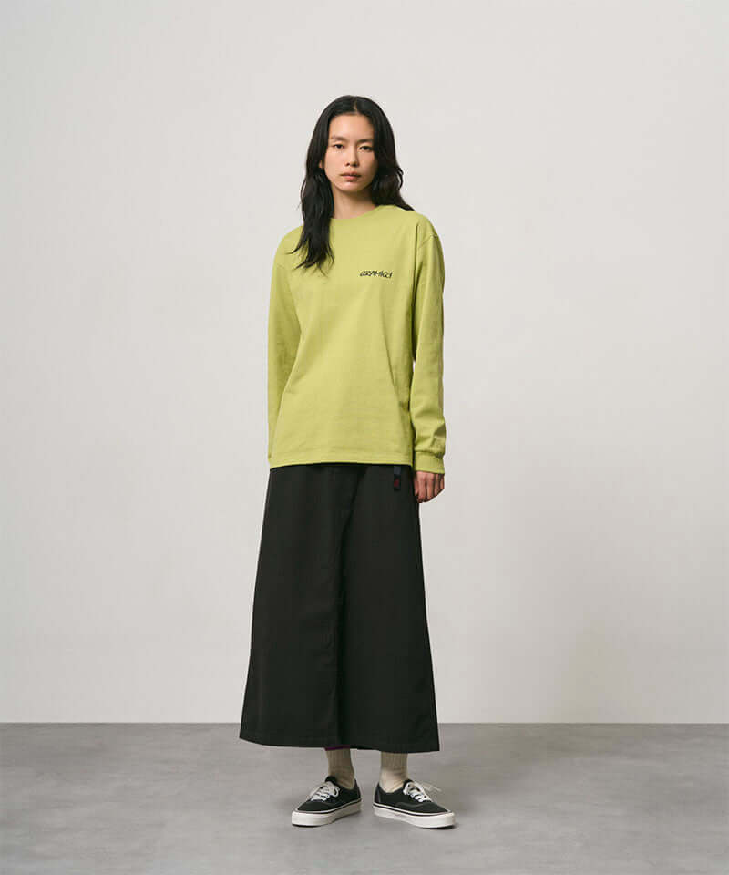 Model wearing a black Gramicci 5-Pocket Skirt and a lime green shirt on a light-tone background.