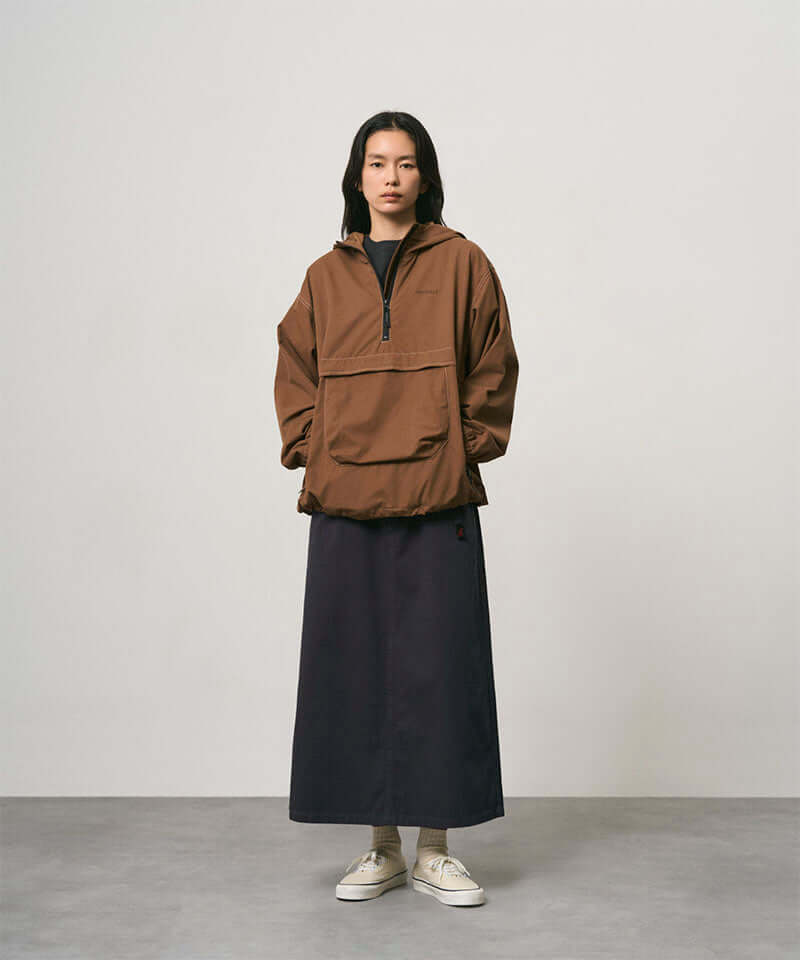 Model wearing a double navy Gramicci 5-Pocket Skirt and a brown jacket on a light-tone background.