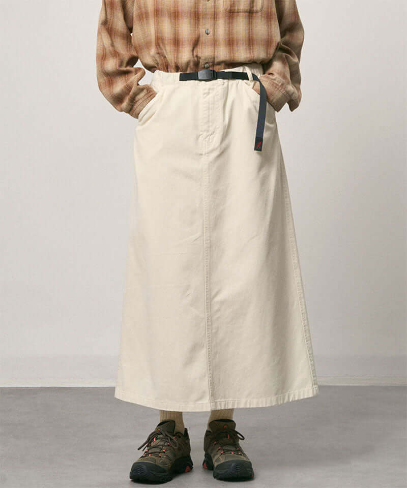 Model wearing a greige colored Gramicci 5-Pocket Skirt and a brown plaid shirt on a light-tone background.