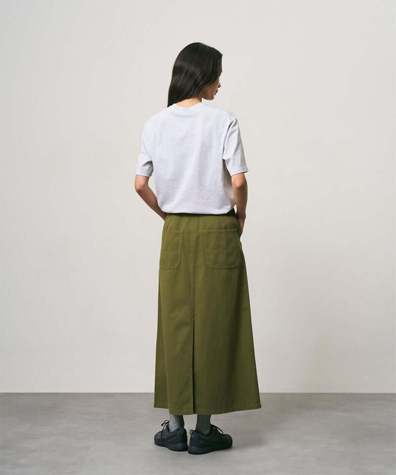 Back view of a model wearing a olive colored Gramicci 5-Pocket Skirt and a white shirt on a light-tone background.