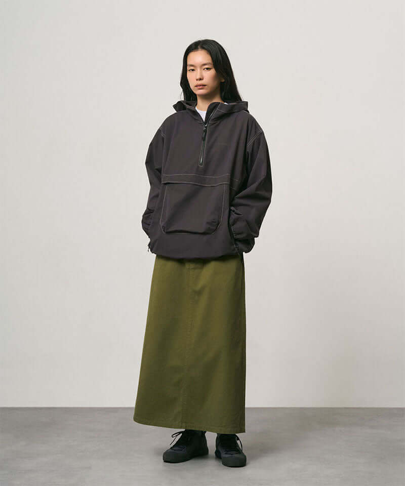 Model wearing a olive colored Gramicci 5-Pocket Skirt and a dark grey jacket on a light-tone background.