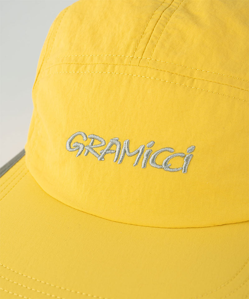 Close-up of a banana colored Nylon Gramicci Cap with a logo on a light tone background.