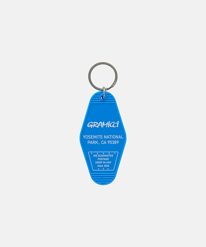 Blue Gramicci Hotel Keychain against a light-tone background.