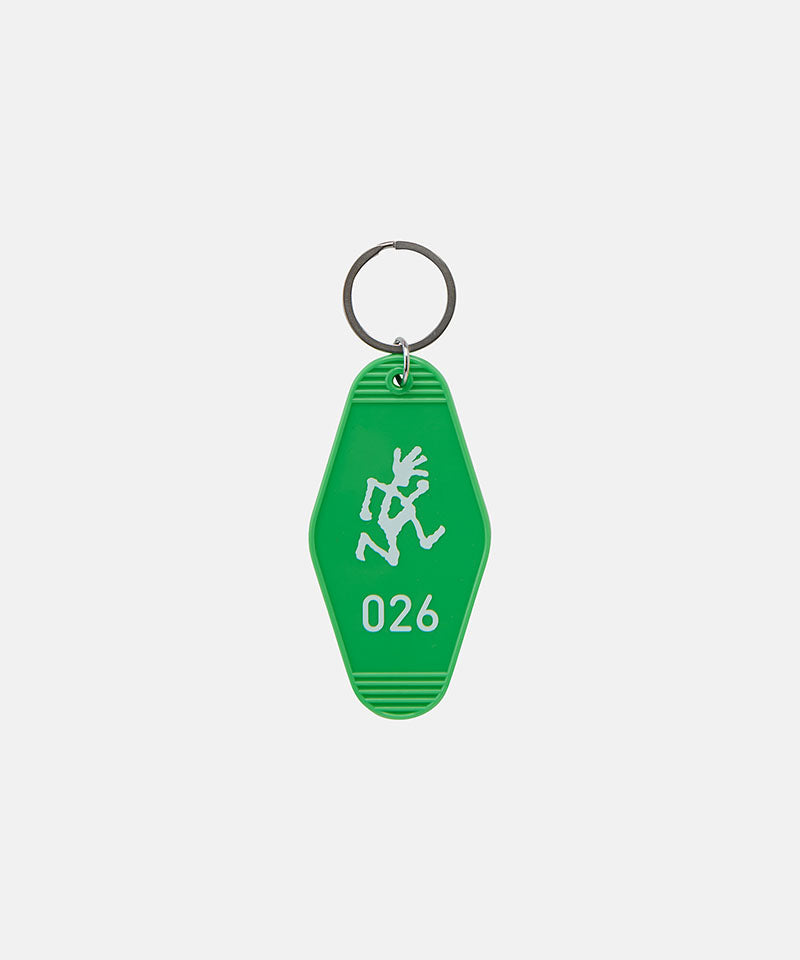 Green Gramicci Hotel Keychain against a light-tone background.