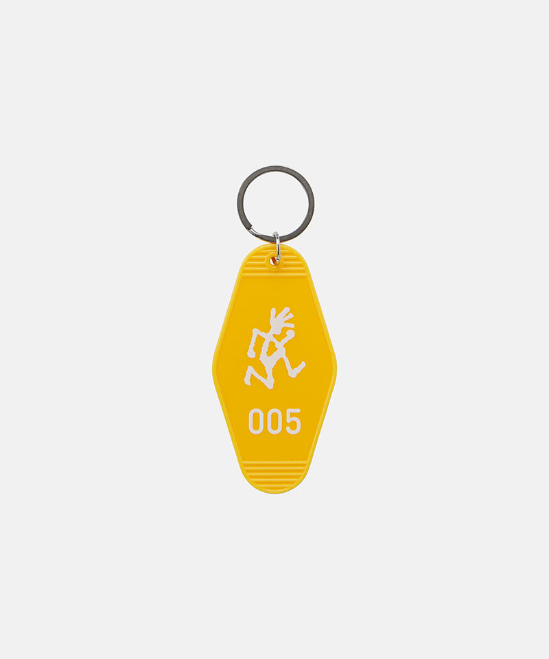 Yellow Gramicci Hotel Keychain against a light-tone background.