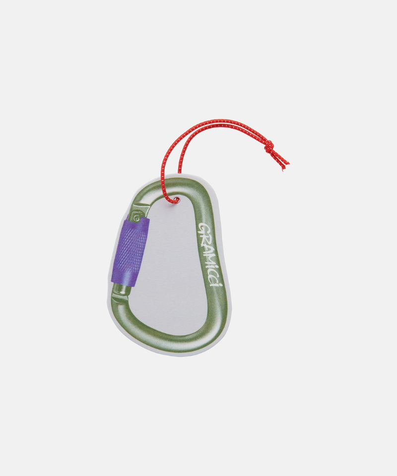 Olive Gramicci & retaW Carabiner Car Tag air freshener against a light-tone background.