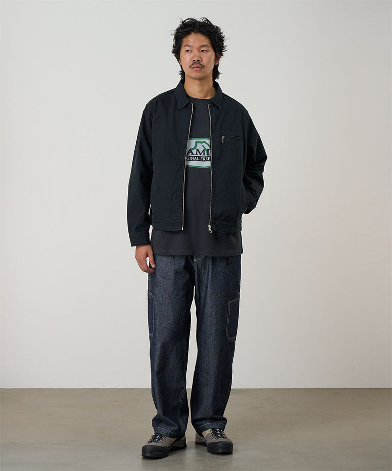 Model wearing a black Gramicci Taos Canvas Jacket and blue jeans on a light-tone background.