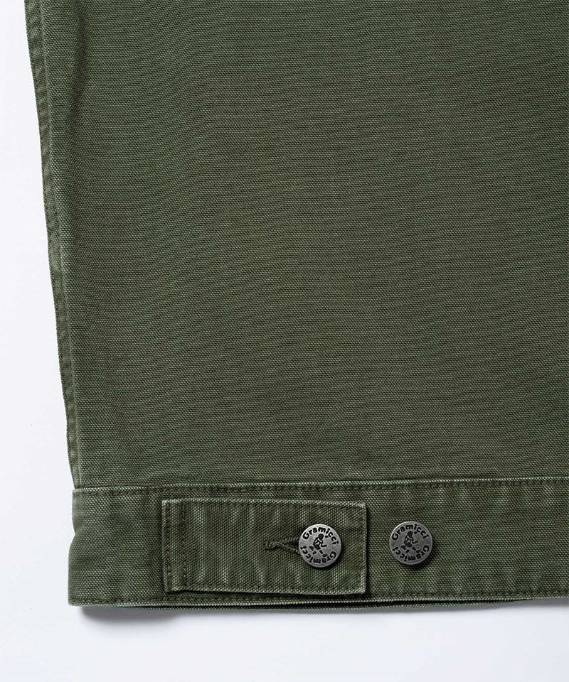 Close-up of a moss green Gramicci Taos Canvas Jacket on a light-tone background.