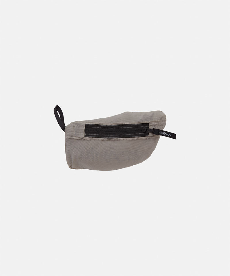 Gramicci concrete colored Ultra-Light Packable Jacket in pouch against a light-tone background.