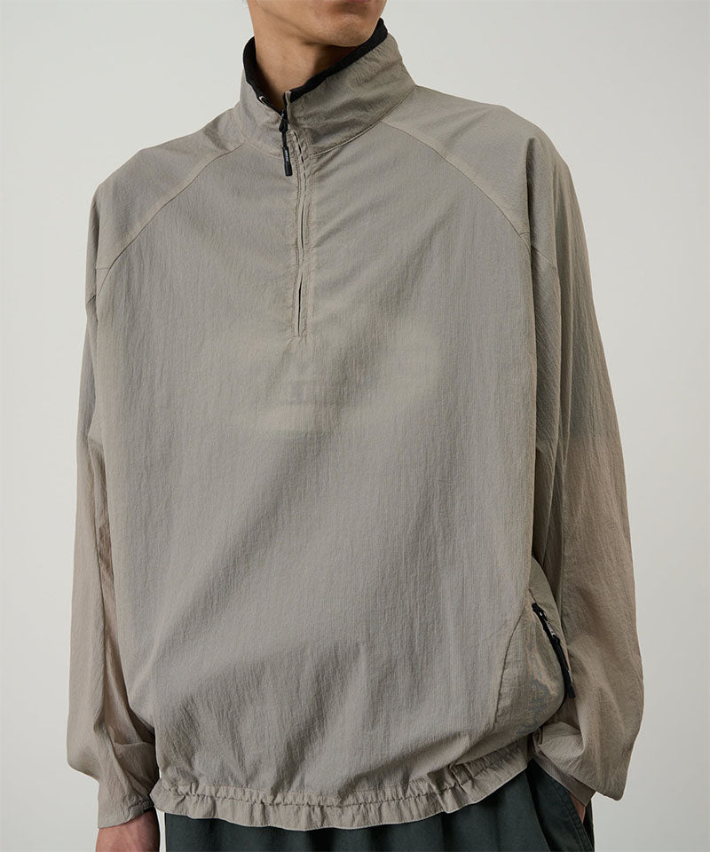 Model wearing a concrete colored Gramicci Ultra-Light Packable Jacket against a light-tone background.