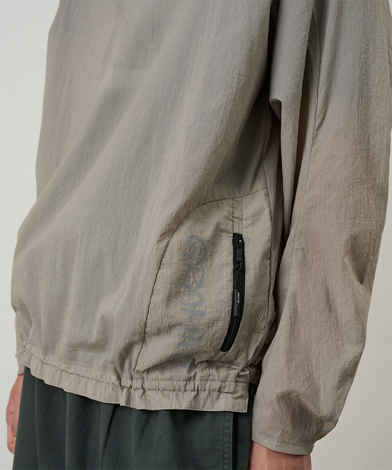 Model wearing a concrete colored Gramicci Ultra-Light Packable Jacket against a light-tone background.