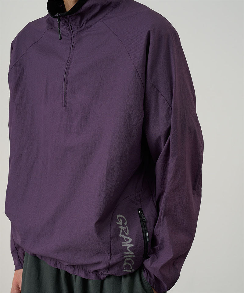 Model wearing an iris purple Gramicci Ultra-Light Packable Jacket against a light-tone background.