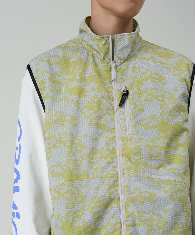 Person wearing a light-colored jacket with a subtle pattern on a plain background