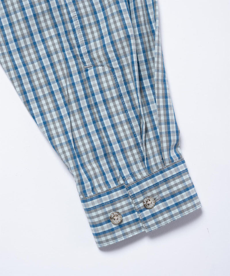 Close-up of the cuff and sleeve on a blue plaid Gramicci Poplin Millwood Shirt on a light-tone background.
