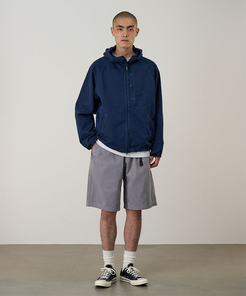 Model wearing a Gramicci Natural Dyed Jam Short in the color grey and a blue hoodie on a light-tone background.