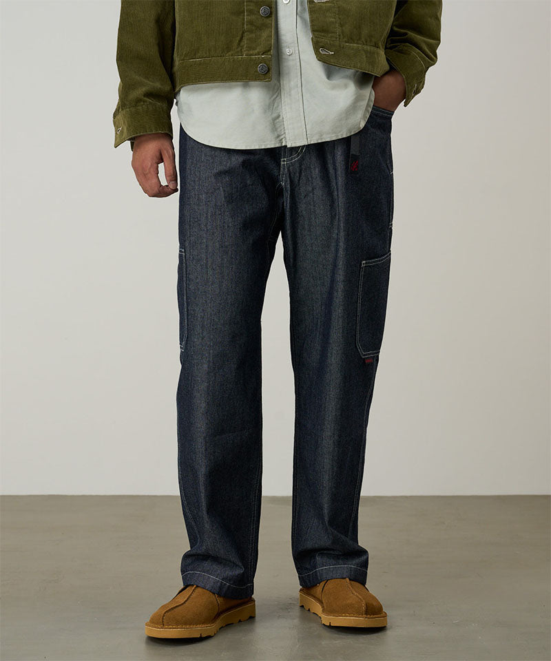 Model wearing navy Japanese Chambray Rock Slide Pant and a moss green jacket on a light-tone background.