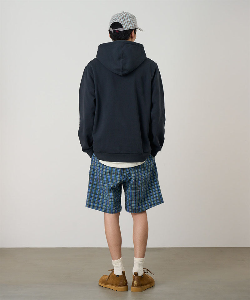 Back view of a model wearing a blue multistripe Gramicci Gramicci O.G. G-Short Seersucker Plaid and navy hoodie on a light-tone background.
