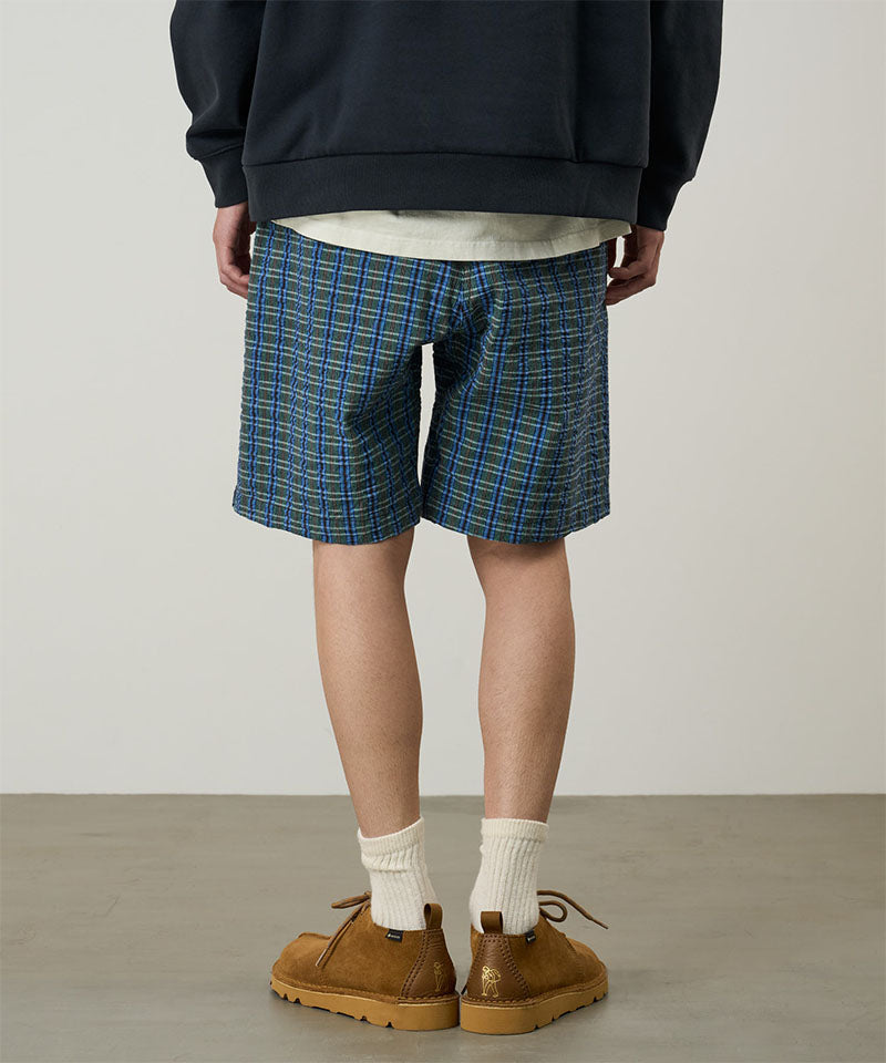 Back view of a model wearing a Gramicci blue multistripe Gramicci O.G. G-Short Seersucker Plaid against a light-tone background.