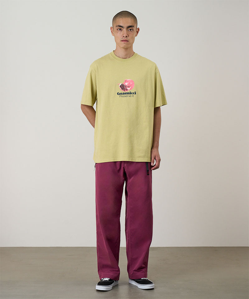 Model wearing burgundy Gramicci Milton Pants and a lime green shirt on a light-tone background.