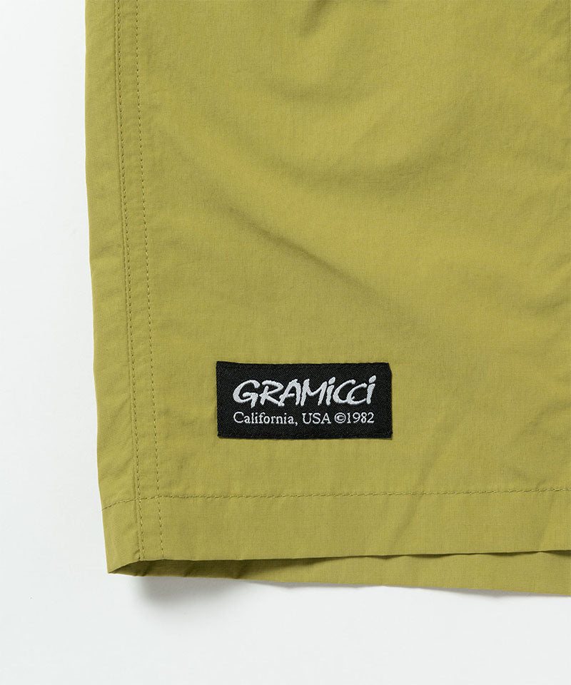 Close-up of a green shorts with a Gramicci logo on a white background