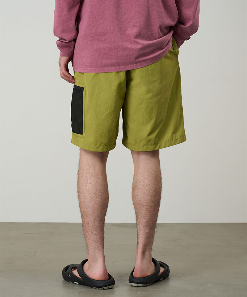 Person wearing green shorts and a red shirt on a plain background