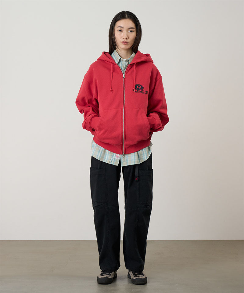 Person wearing a red hoodie with a logo, black pants, and plaid shirt on a plain background