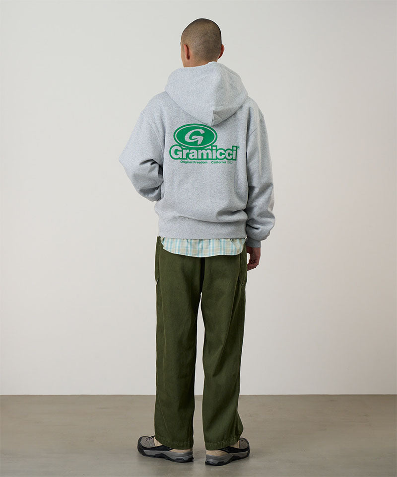 Person wearing a gray hoodie with a visible brand logo, standing against a plain background