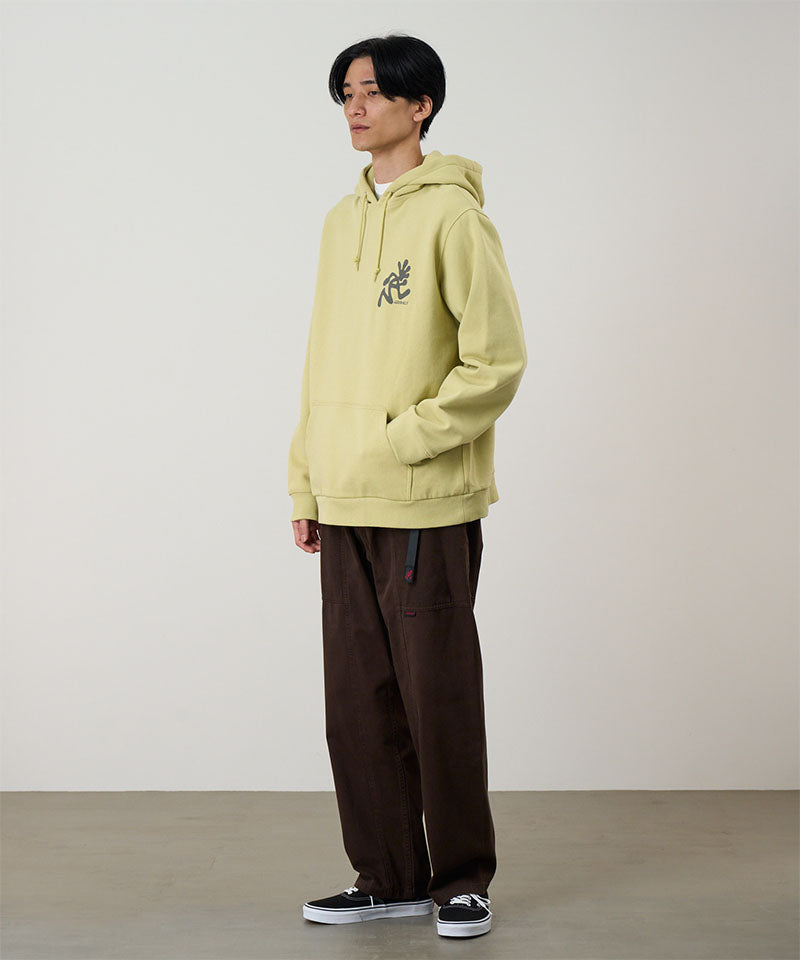 Person wearing a light yellow hoodie with a logo, standing against a plain background
