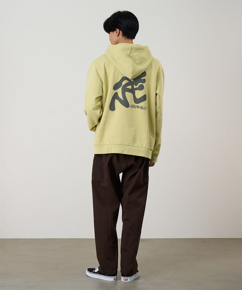 Person wearing a light green hoodie with black text on the back, standing against a plain background.