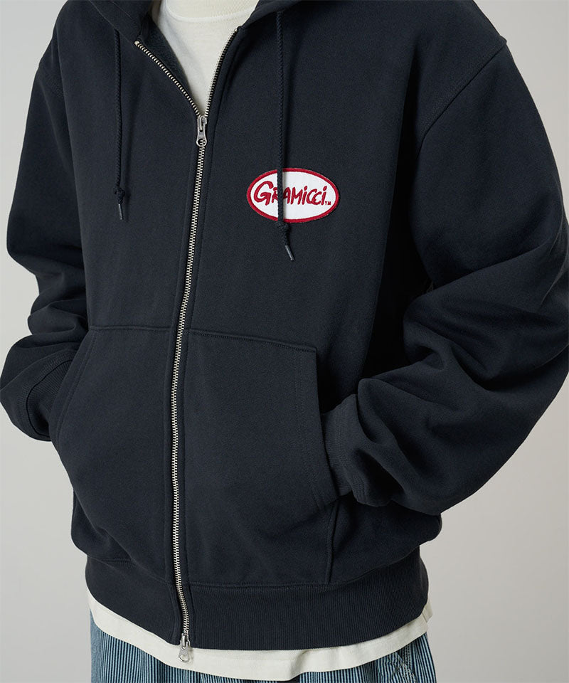 Black zip-up hoodie with a logo on the chest against a gray background