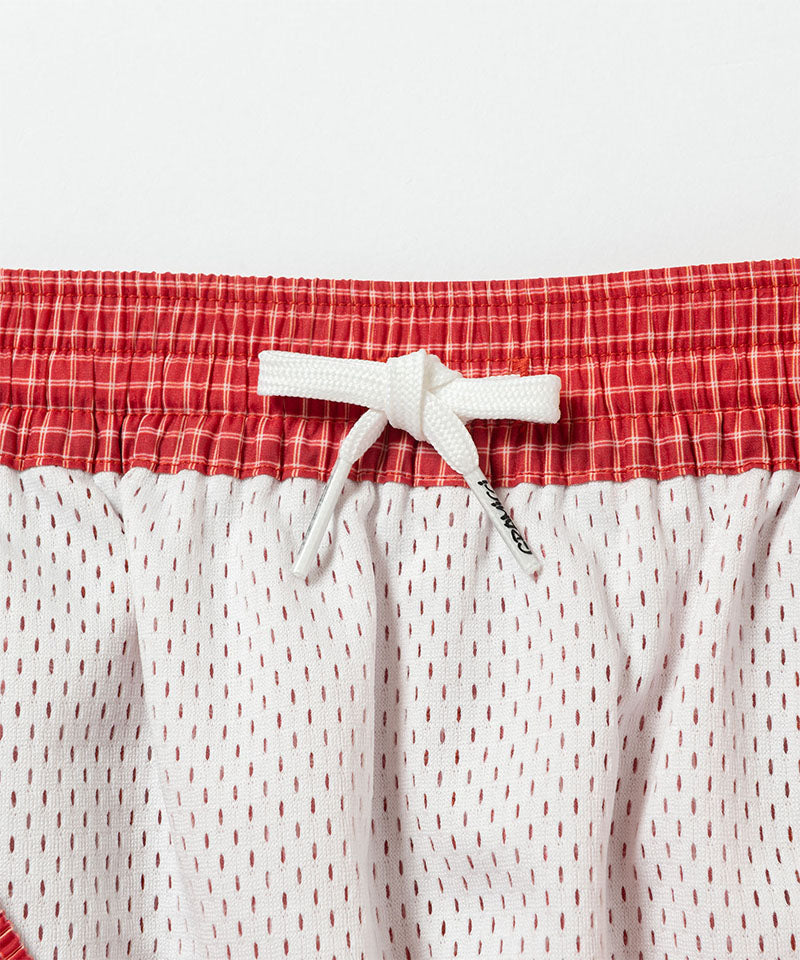 Front view close-up of red and white Gramicci Grid Swim Shorts against a light-tone background.