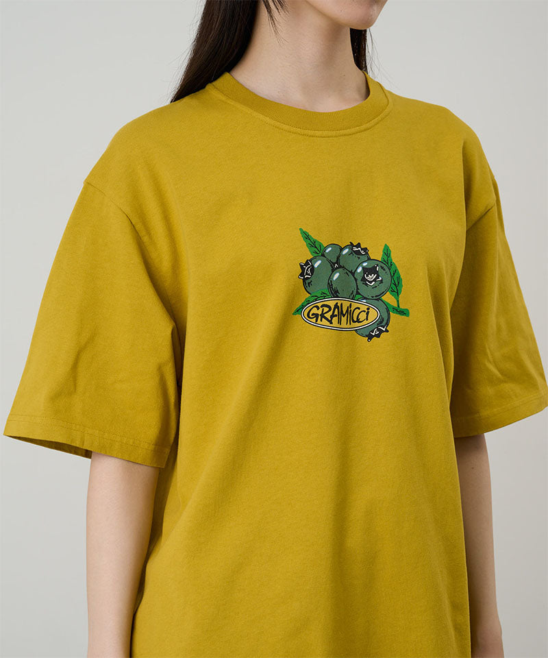 Gramicci Blueberry Tee featuring a blueberry graphic in yellow worn by a model against a light tone background.