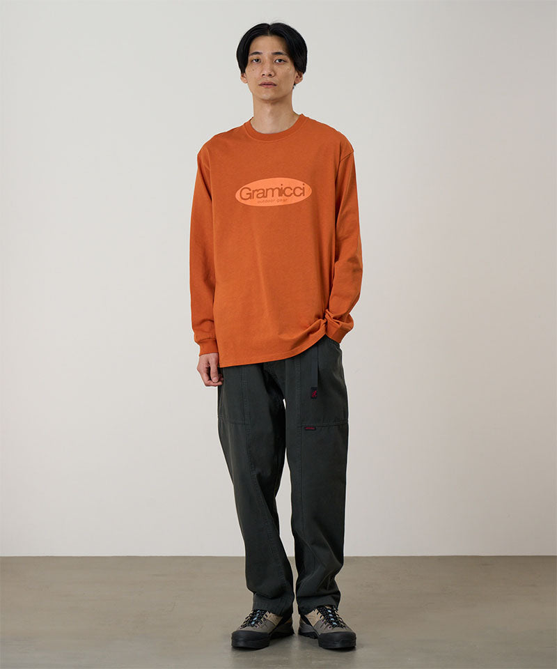 Model wearing a orange Gramicci Gramicci Outdoor Gear L/S Tee with a light orange graphic and dark pants on a light-tone background.