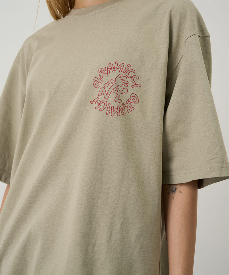 Model wearing a beige Gramicci Running Man Tee with graphic against a light tone background.