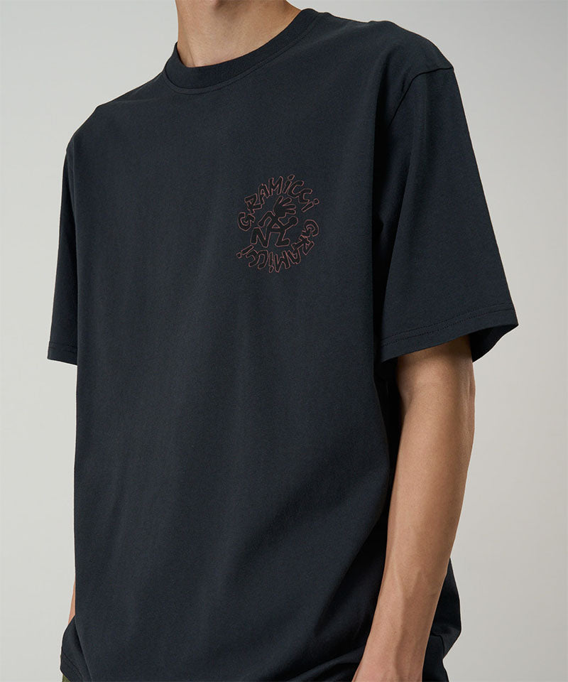 Model wearing a black Gramicci Running Man Tee with graphic against a light tone background.