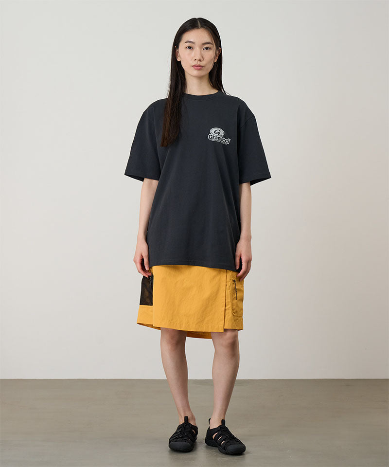 Model wearing a vintage black Gramicci '82 Tee with a beige graphic and yellow skort on a light tone background.