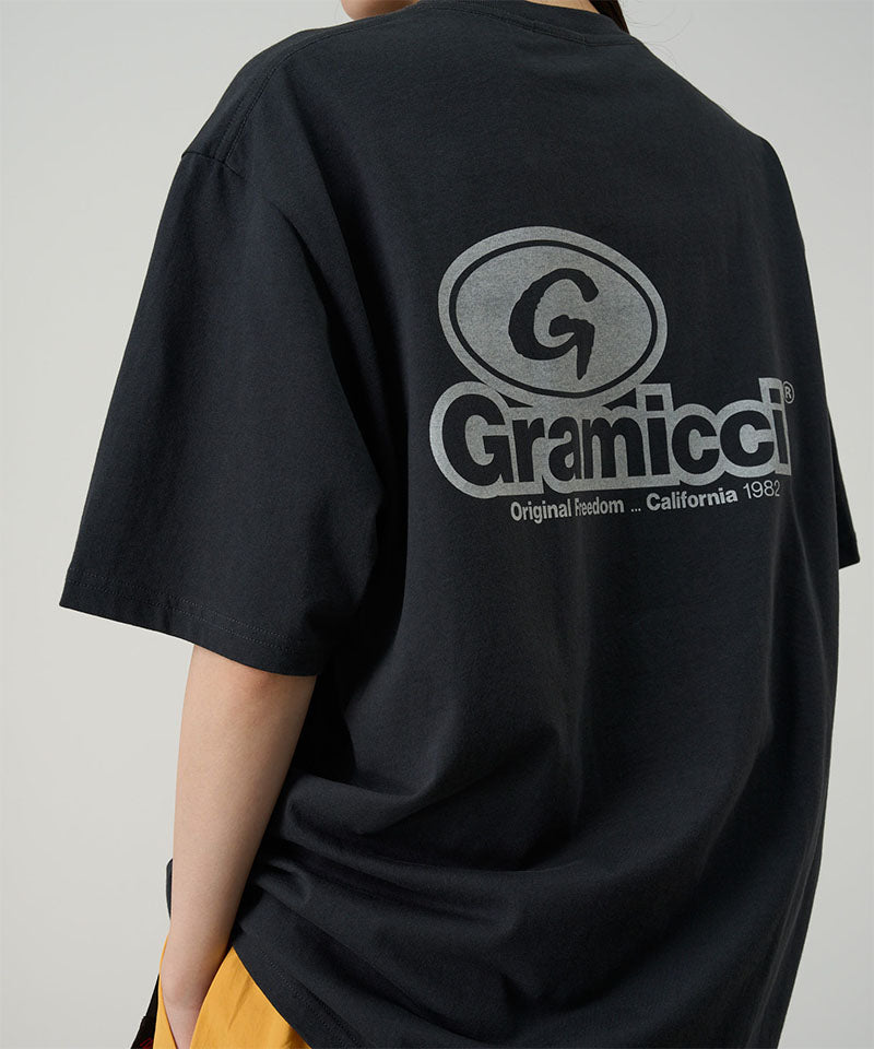 Rear view of a model wearing a vintage black Gramicci '82 Tee on a light tone background.